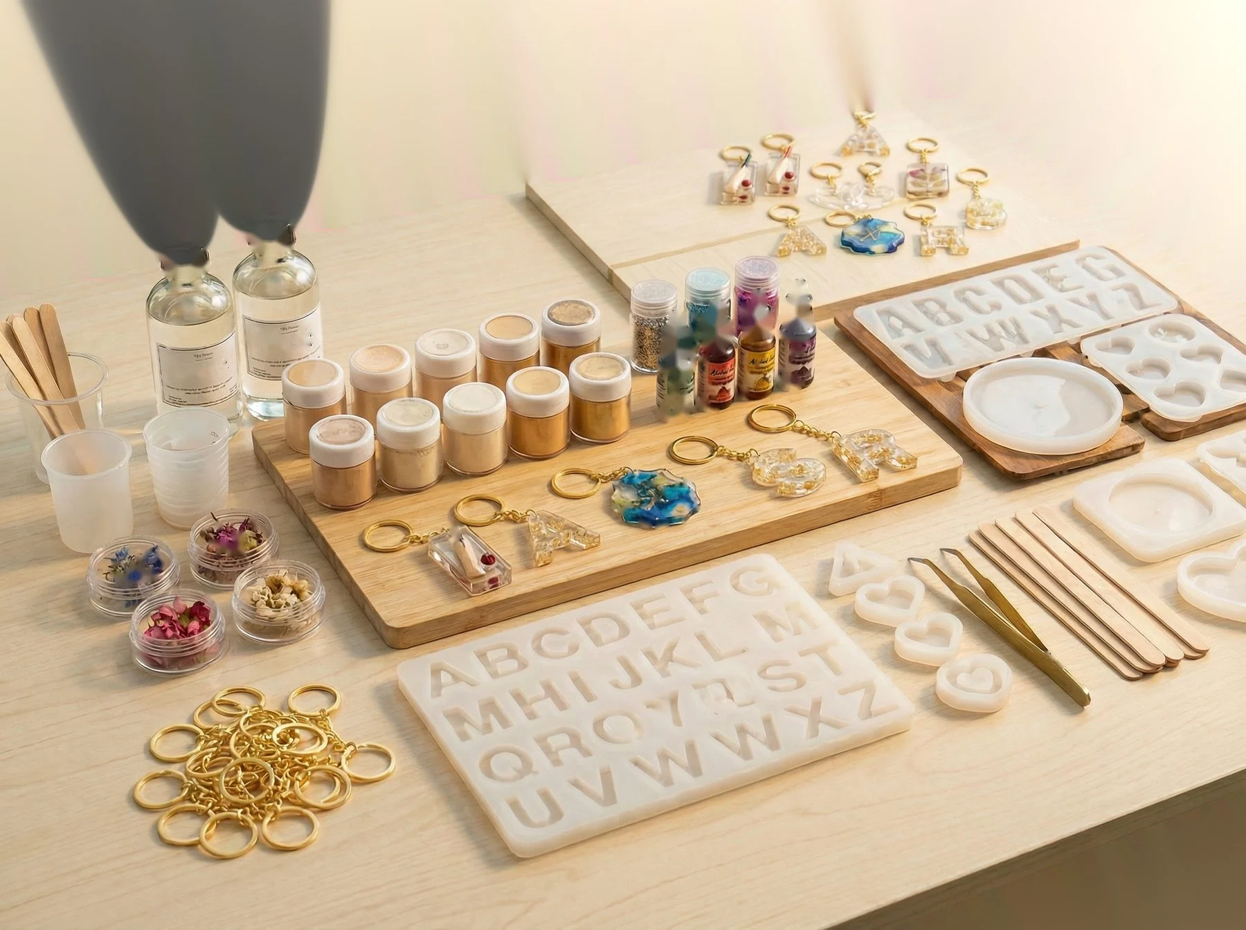 Close-up of resin bottles, pigment jars, and glitter arranged neatly. 400x280px