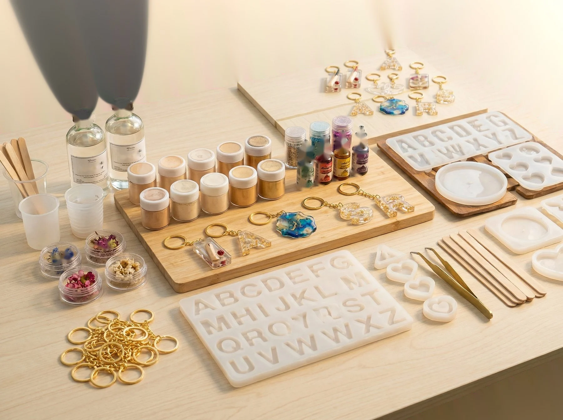 Your workspace with resin bottles, pigments, moulds, glitter, and tools arranged neatly. Show raw materials. 600x500px